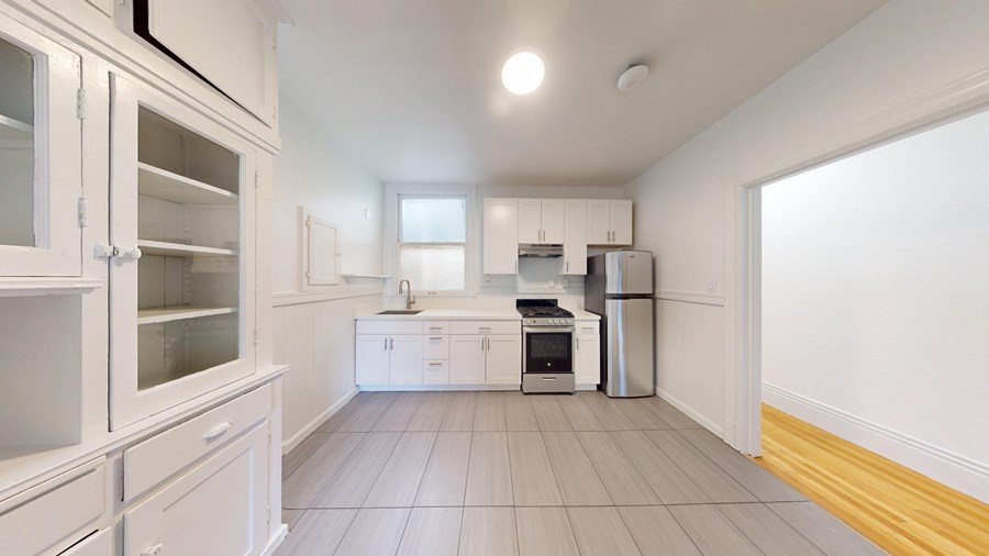 A kitchen with white cabinets and appliances.